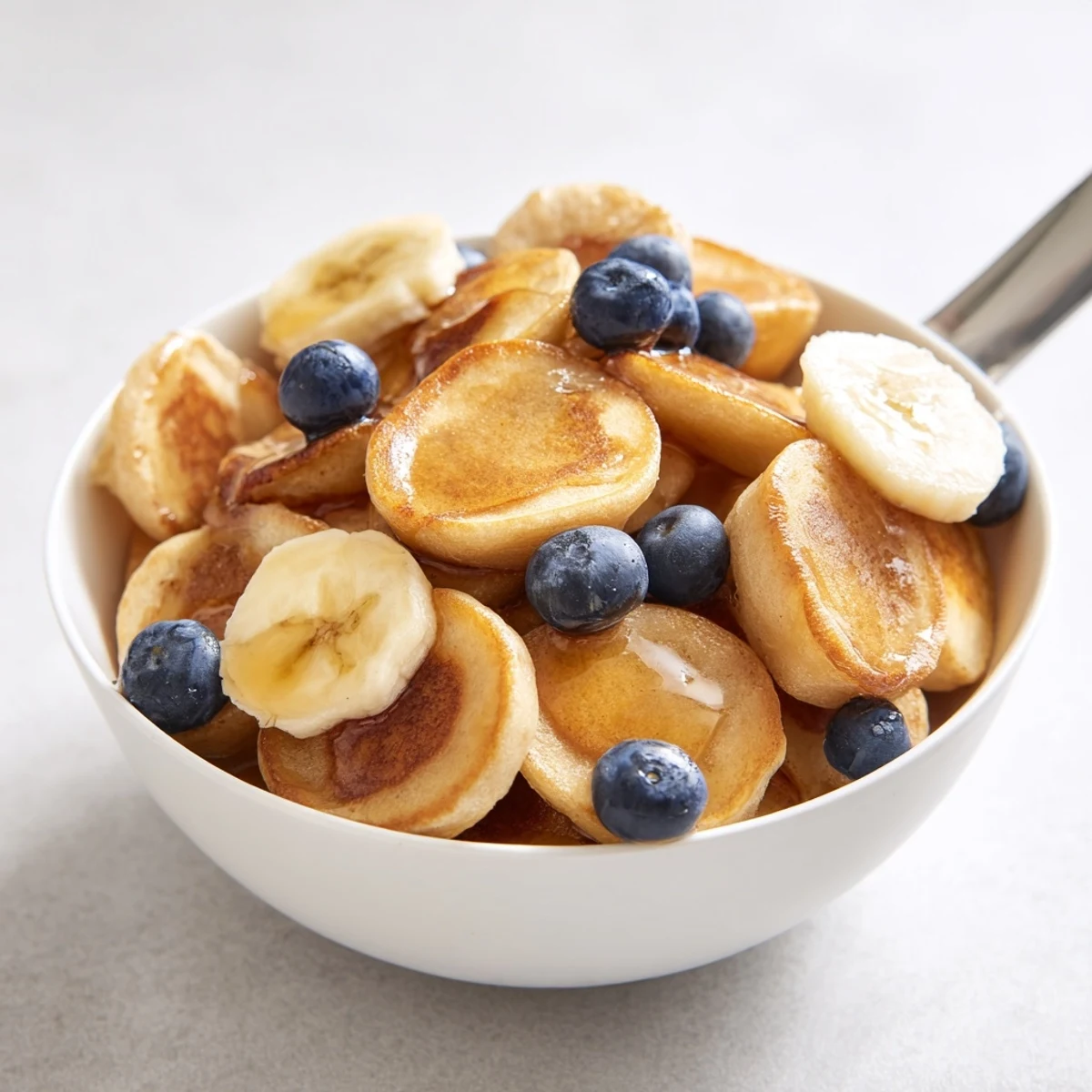 Delicious mini pancake cereal topped with fresh berries and maple syrup.  