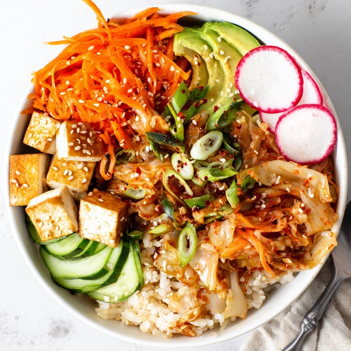 Colorful bowl of fermented vegetables featuring kimchi, avocado, and savory sesame dressing.