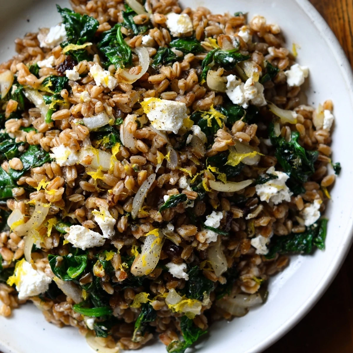 A vibrant bowl of warm Farro & Greens Pilaf, topped with toasted, flavorful almonds.