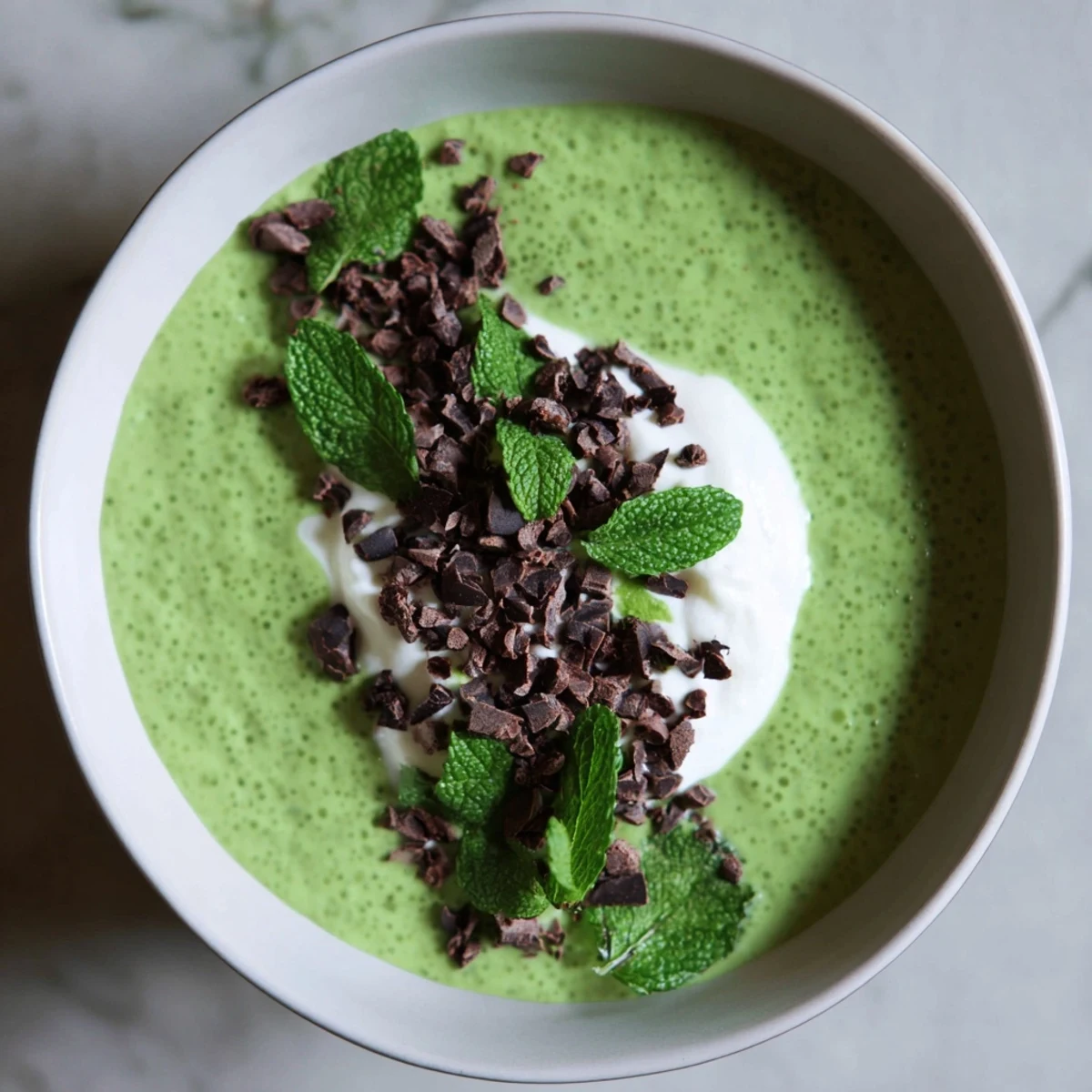 Grinch Green Mint Matcha Breakfast Chia Pudding, topped with yogurt, chocolate chips, and fresh mint on display.