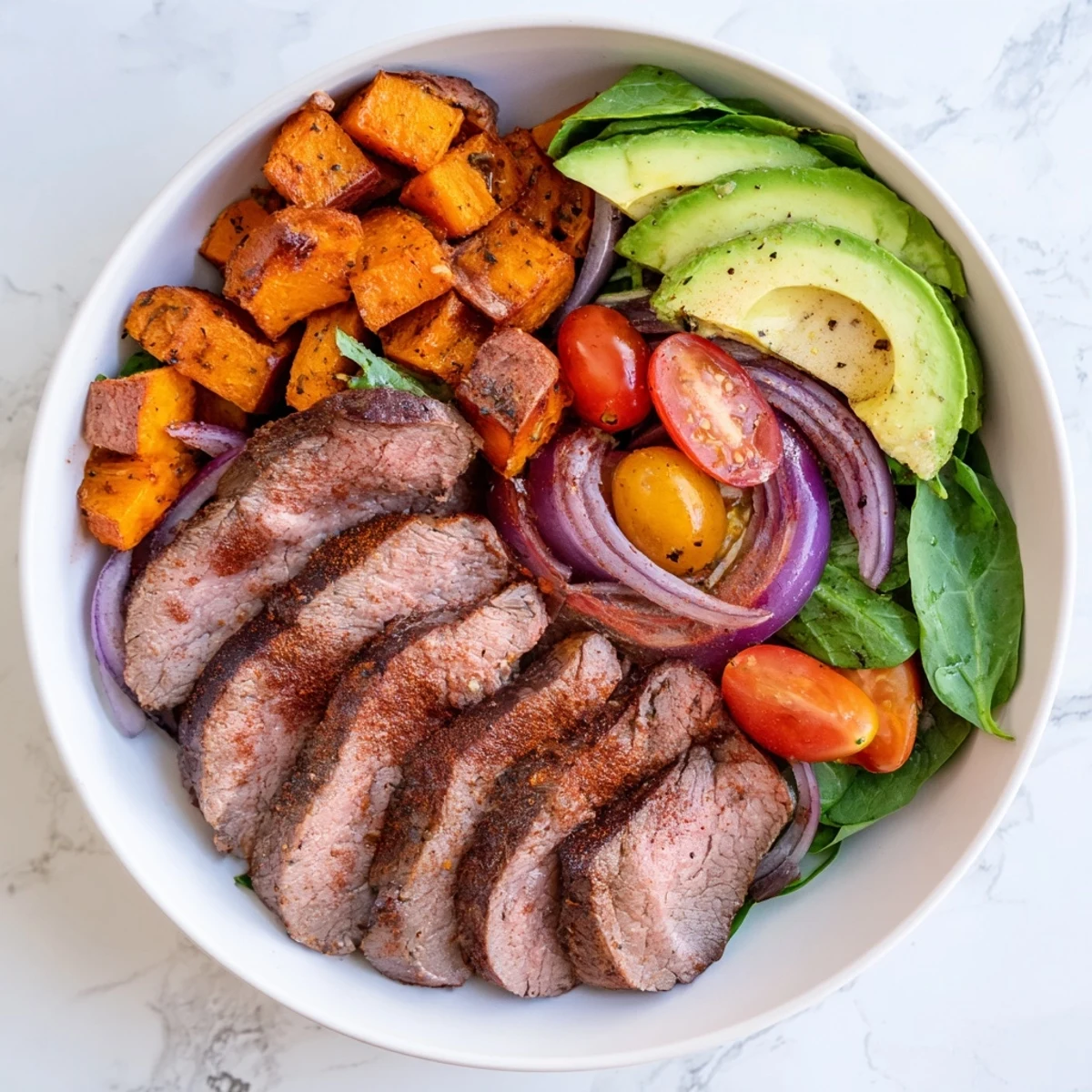 This colorful Beef Avocado Sweet Potato Bowl features seared beef with vibrant tomatoes and a creamy yogurt dressing.