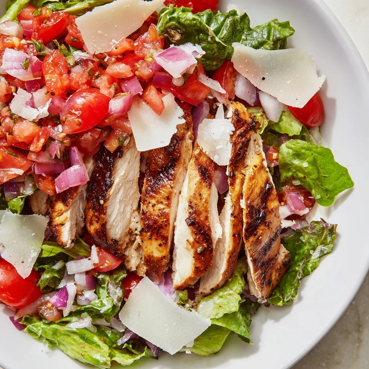 Freshly grilled chicken slices are topped with a vibrant tomato-basil mixture and served over crisp mixed greens for Bruschetta Chicken Salad.