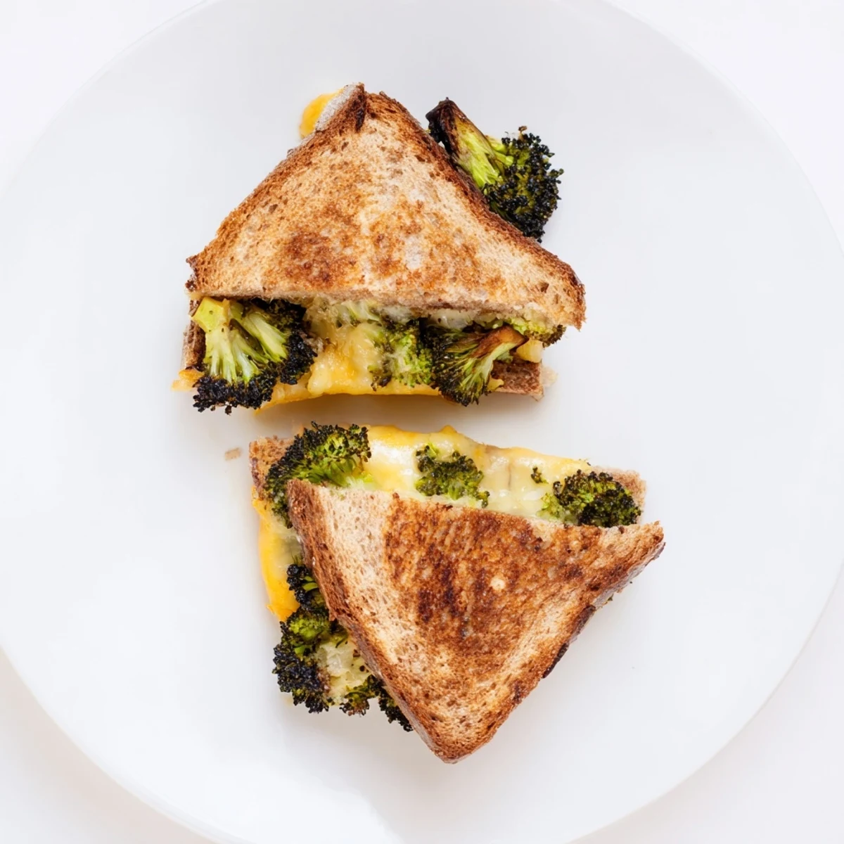 Melted sharp cheddar and roasted broccoli nestled between crispy, golden-toasted sandwich bread slices.