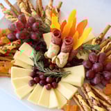 Arrangement of the Flicker Fire Log Snack Board shows various cheeses and fruits, like a burning fire log.