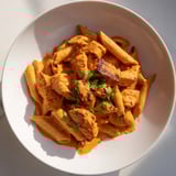 Golden, charred chicken tikka and al dente penne pasta tossed in a rich, spiced tomato-cream sauce, ready to serve.
