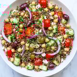 Hearty Greek Power Salad featuring protein-packed lentils, quinoa, chickpeas, and crisp veggies topped with feta.