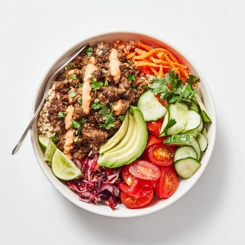 Vibrant plant-based meat bowl with fresh veggies and spicy mayo drizzle.  