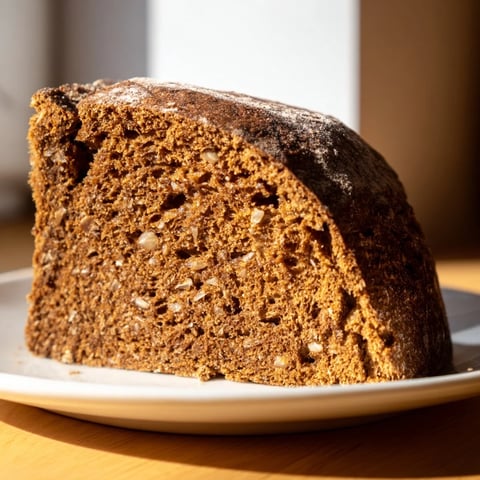 Crusty Latvian Rupjmaize bread, studded with caraway seeds, ready to be sliced for a sandwich.