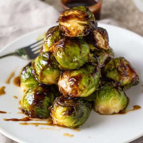 Golden roasted Brussels sprouts glistening with balsamic glaze, served warm on a rustic platter for a savory side dish.