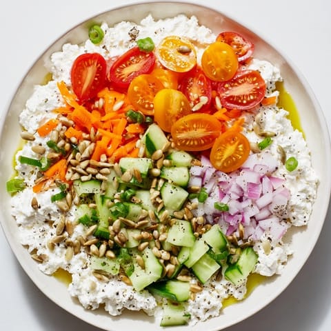 Creamy cottage cheese snack bowl, a high-protein treat with colorful veggies and crunchy toppings.
