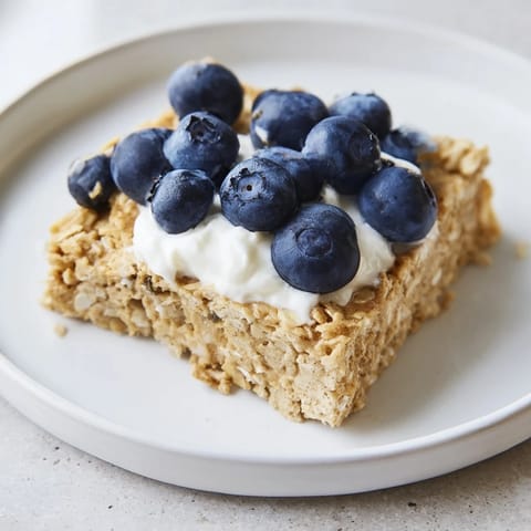A close-up of warm, sliced Protein Pancake Oats, ready to be topped with fresh fruit and syrup.