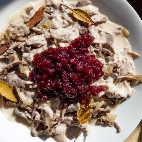 Hearty Finnish Reindeer Stew, with tender meat and onions, presented with creamy mashed potatoes and lingonberries.