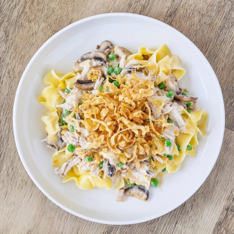 Steaming hot creamy tuna noodle casserole with a bubbly, golden crispy onion crust.