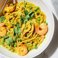 Bright Yellow Curry Shrimp Pasta tossed with vibrant peas and fresh coriander.  