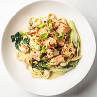 Creamy miso butter salmon pasta, served with vibrant bok choy and fresh scallions, is ready to savor.