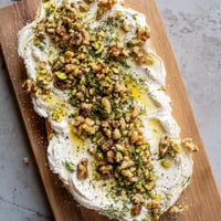 Creamy Flavored Butter Board with nuts, herbs, and honey, ready to serve with bread.